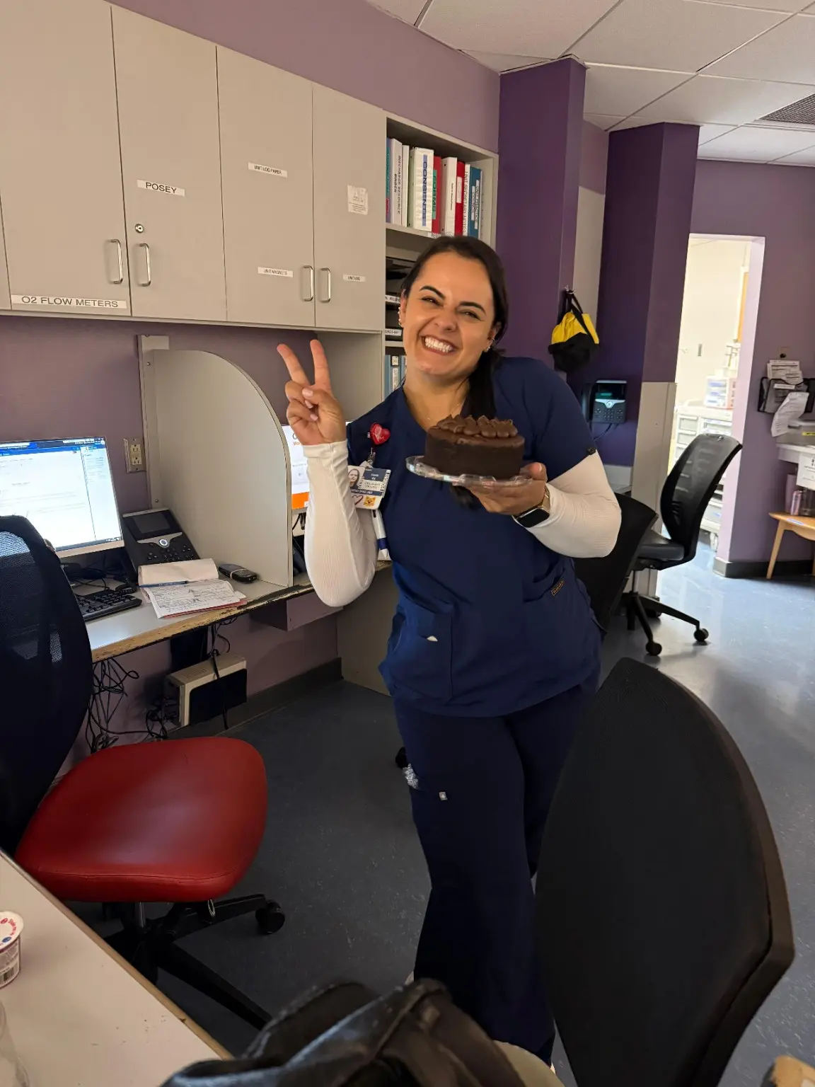 Camila smiling in nursing scrubs inside the healthcare unit where she works